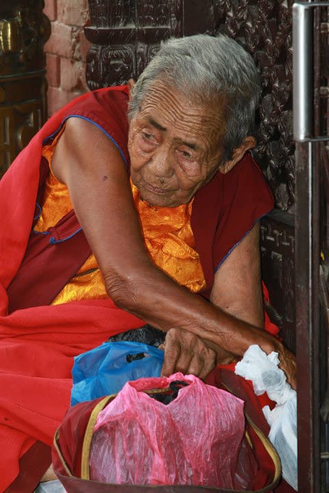 Egy idős szerzetes hölgy egy kathmandui Nyingma kolostor előtt